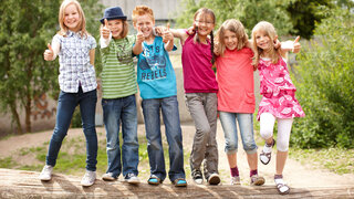 Gruppe fröhlicher Kinder auf Baumstamm