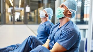 Zwei erschöpfte Chirurgen in blauer OP-Kleidung
