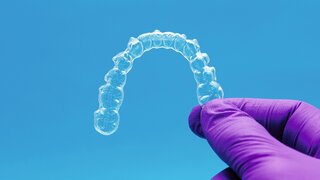 Behandschuhte Hand hält Aligner