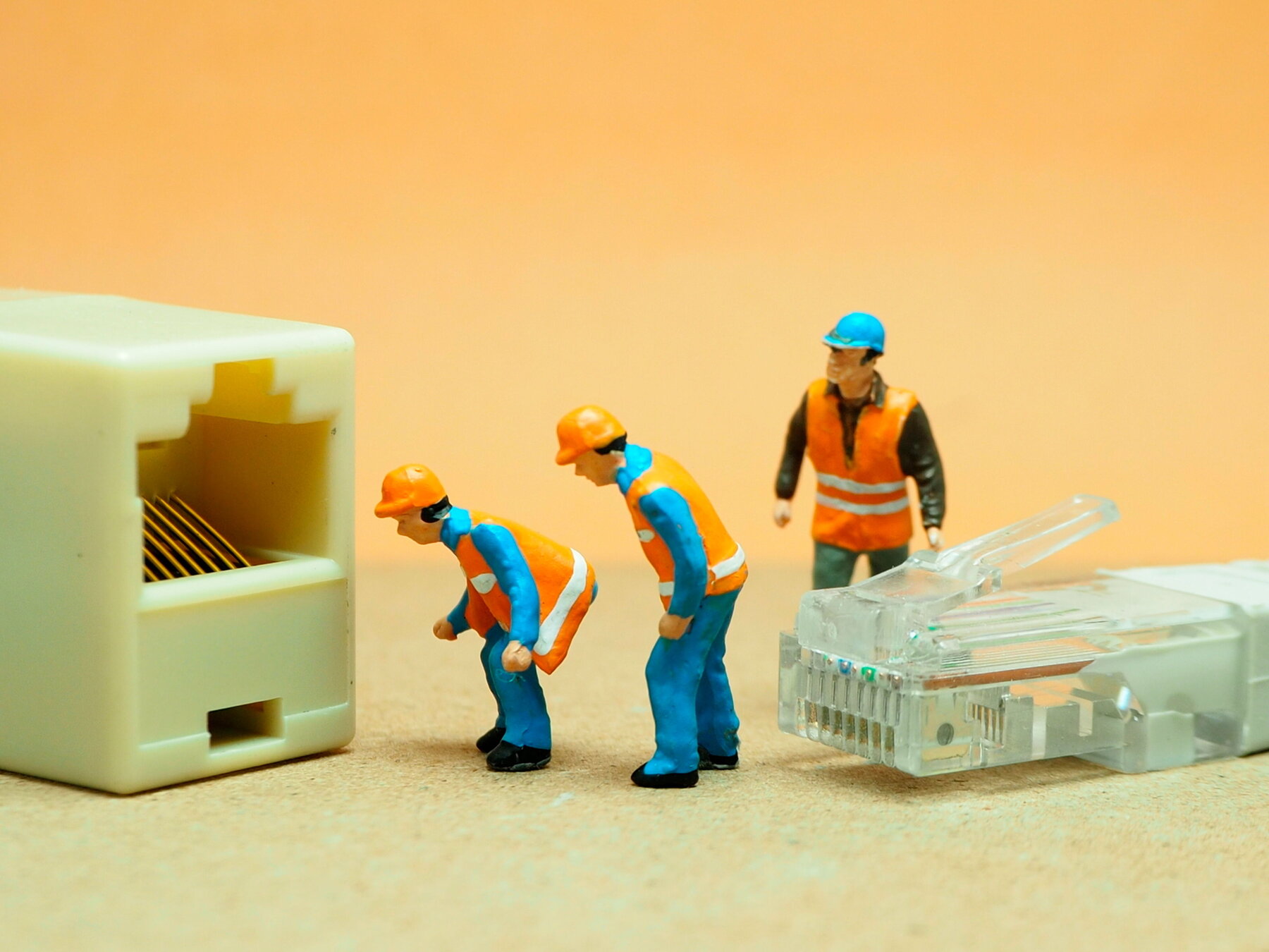 Mini-Actionfigur im Freien mit unscharfem Hintergrund. IT-Ingenieur mit UTP-Kabel.