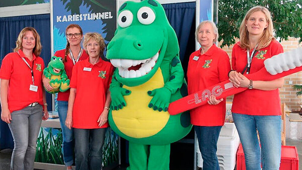 Berlin: Mit Kroko im Kariestunnel Zusammen mit Zahnärztinnen des Zahnärztlichen Dienstes (ZÄD) des Bezirks Lichtenberg waren Mitarbeiterinnen der Landesarbeitsgemeinschaft Berlin zur Verhütung von Zahnerkrankungen (Gruppenprophylaxe) e.V. (LAG) in der Carl-von-Linné-Schule in Berlin-Lichtenberg. Die 1977 gegründete Ganztagsschule Carl-von-Linné in Berlin-Lichtenberg ist mit über 340 Schülerinnen und Schülern die größte Schule für behinderte Kinder in Europa. Zuerst färbten die Kinder mit einem fluoreszierenden Mittel ihre Zähne an. Dann gingen oder fuhren die Kinder mit ihren Rollstühlen in den Kariestunnel. Im Schwarzlicht leuchteten die Beläge an den Stellen, an denen nicht richtig geputzt worden war, gelb. Anschließend wurden die Beläge unter fachkundiger Anleitung mit der richtigen Putztechnik beseitigt. Bei einem zweiten Gang durch den Kariestunnel konnten sich die Kinder davon überzeugen, wie wirkungsvoll das richtige Zähneputzen gewesen ist. Die Zahnärztinnen des ZÄD gaben den Kindern und Lehrerinnen und Lehrern abschließend noch wertvolle Tipps zur Mundhygiene.