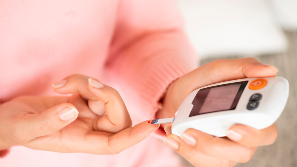 Nahaufnahme von Frauenhänden, die den Blutzuckerspiegel mit einem Glukosemessgerät für Diabetes-Tester überprüfen