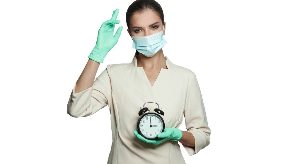 Zahnärztin, die einen Wecker in der Hand hält.