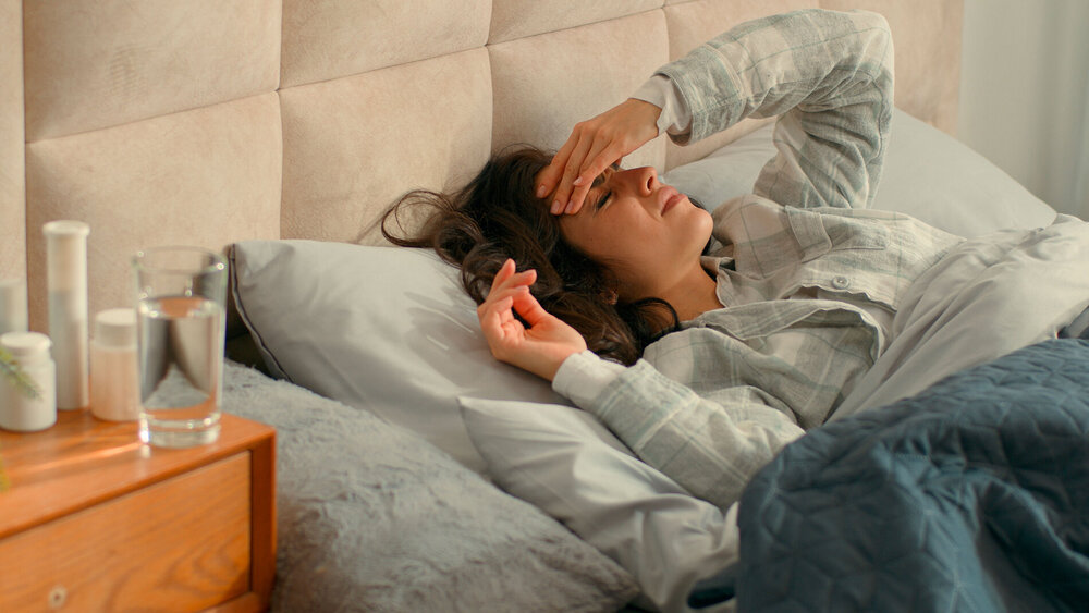 Frau mit Kopfschmerzen im Bett