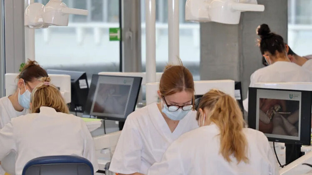 Je zwei Studierende üben die Behandlungssituation gemeinsam an einem Simulationsarbeitsplatz.