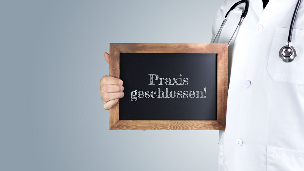 Praxis geschlossen!. Arzt zeigt Begriff auf einem Holz Schild. Handschrift auf Tafel Praxis geschlossen!. Arzt zeigt Begriff auf einem Holz Schild. Handschrift auf Tafel