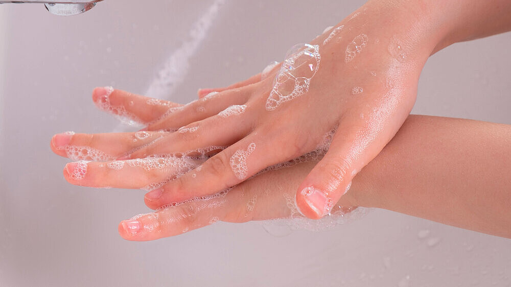 young girl soaped her hands and holds them under the tap in the bathroom young girl soaped her hands and holds them under the tap in the bathroom in the morning