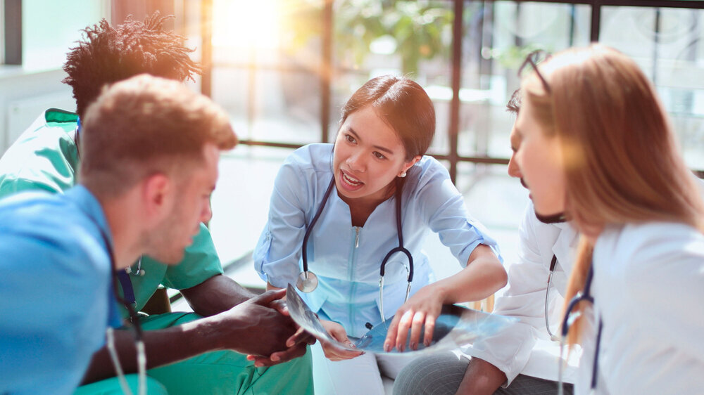 Praxisteam in der Teambesprechung Ein interprofessionelles berufsübergreifendes Team von Gesundheitsfachkräften tauscht sich aus
