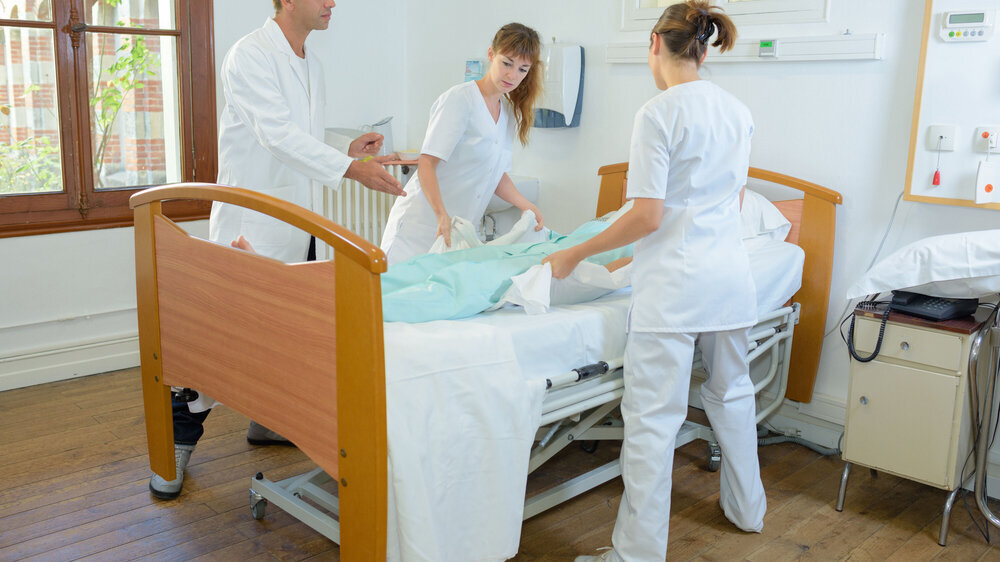 Junge Pflegekräfte mit Patient unter Supervision Ausbilder Junge Pflegekräfte mit Patient unter Supervision Ausbilder
