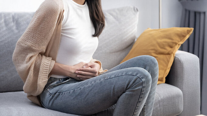 Attractive Asian young woman suffering from stomach ache, gastritis, menstruation, colitis, concept of female stomach ache. Bauchschmerzen