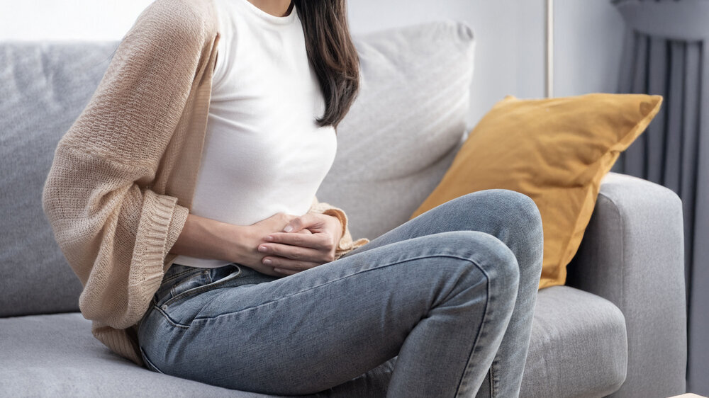 Attractive Asian young woman suffering from stomach ache, gastritis, menstruation, colitis, concept of female stomach ache. Bauchschmerzen