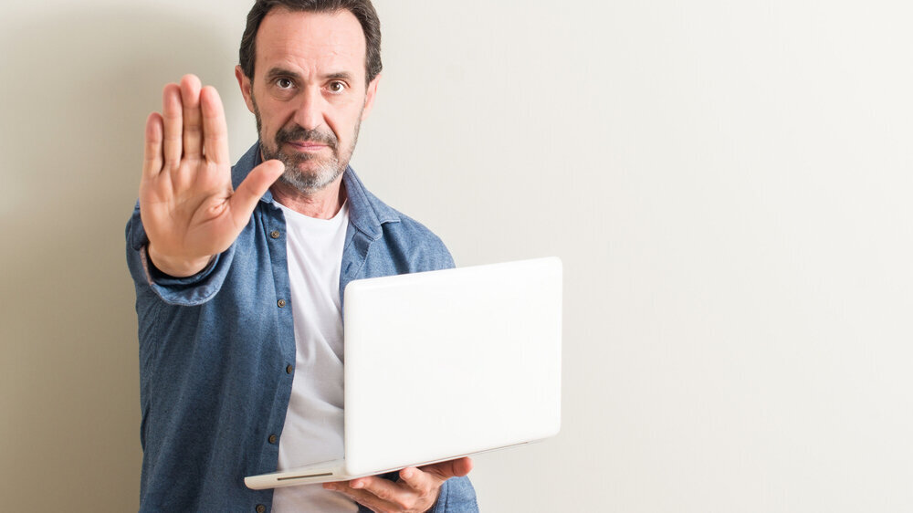 Mann mit Laptop signalisiert Stopp Mann mit Laptop signalisiert Stopp