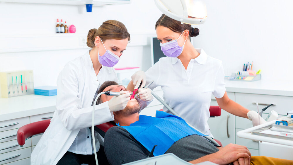 Zahnärztin und Zahnmedizinische Fachangestellte behandeln Patienten.