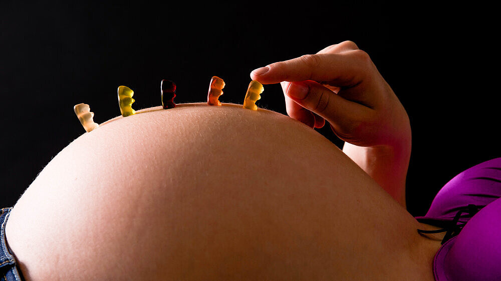 reihe Gummibärchen auf dickem Babybauch