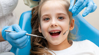 Kleines Mädchen auf dem Behandlungsstuhl beim Zahnarzt.