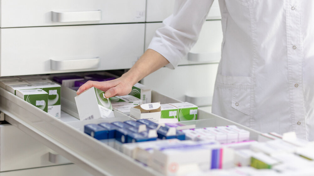 Apothekerin hält Medikamentenschachtel und Kapselpackung in einer Drogerie. Apothekerin hält Medikamentenschachtel und Kapselpackung in einer Drogerie.