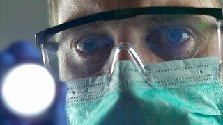 Doctor Using Flashlight on Patient's Eyes Wearing Surgical Mask Glasses POV