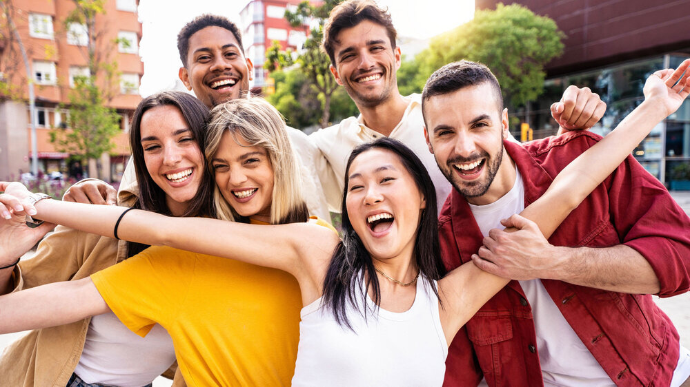 Freunde, die draußen Spaß haben: Eine Gruppe junger Leute, die in die Kamera lächeln.