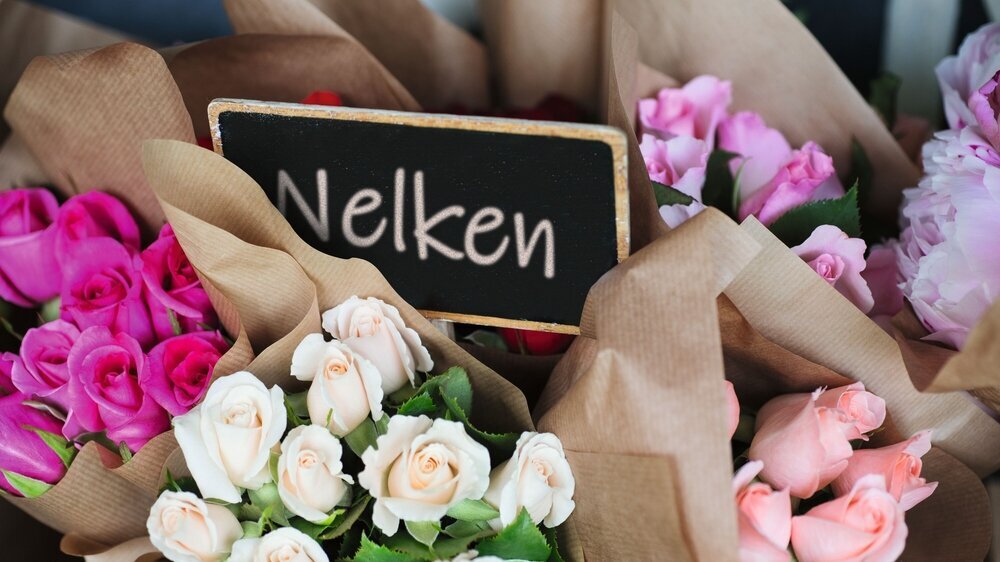 A blank sign in the middle of wrapped bouquets of sorted color roses