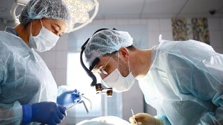 Dental surgery. The surgeon and the assistant. The patient is unrecognizable. Modern dentistry. Photo in the operating room. Concept of healthcare.