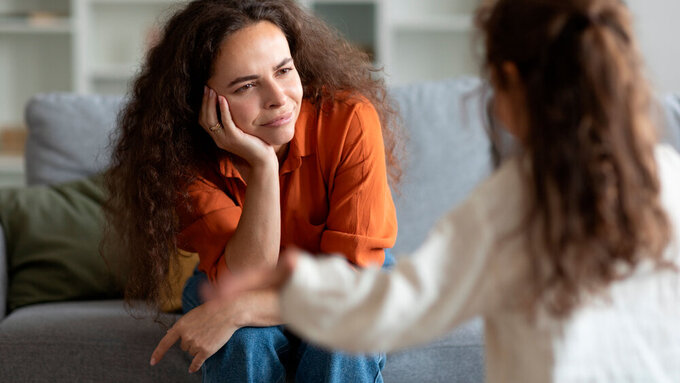 Sad tired mother resting on couch feeling annoyed, does not cope with capricious little kid girl, daughter screaming and being hyperactive Gestresste Mutter