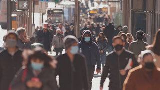 Anonymous crowd of people walking street wearing masks during covid 19 coronavirus pandemic