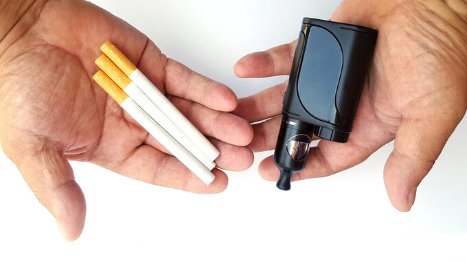 Vaping device and cigarettes in the man's hand, concept of choosing the type of cigarette Vaping device and cigarettes in the man's hand, concept of choosing the type of cigarette