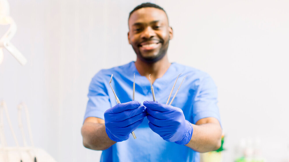 Dentisry concept, healthcare, oral and teeth care. African man dentist holding the dental instruments Schwarzer Zahnarzt