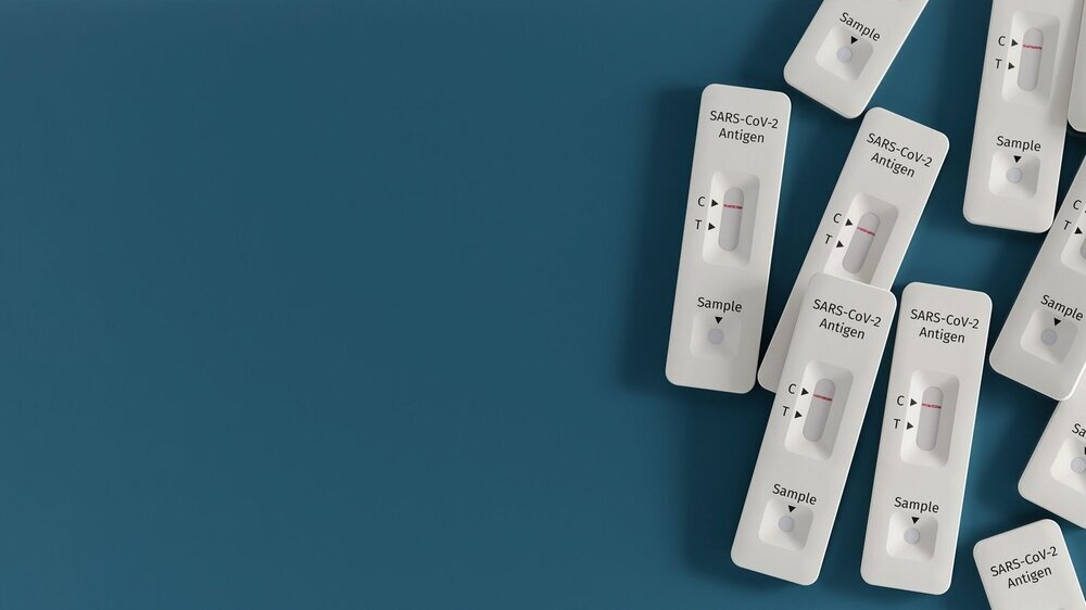 Mass testing for Covid-19 / SARS-CoV-2 infection concept: Several rapid antigen test kits. One kit in the middle showing a positive result (two lines visible) Antigentest, Schnelltest, Covid