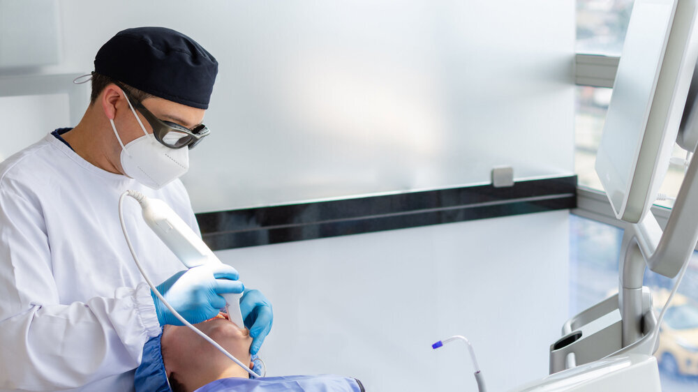 Male dentist performing a scan for the 3d model of a female patient's mouth. Dental clinic concept Zahnarzt mit Maske behandelt