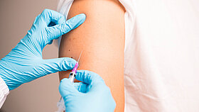 Doctor hand in blue gloves holding influenza vaccine for prevention human.Nurse holding syringe make injection in shoulder of patient in hospital.Covid-19 or coronavirus vaccine.