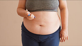 Overweight woman applying diabetes medicine injection into her stomach