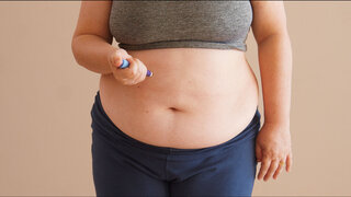 Overweight woman applying diabetes medicine injection into her stomach