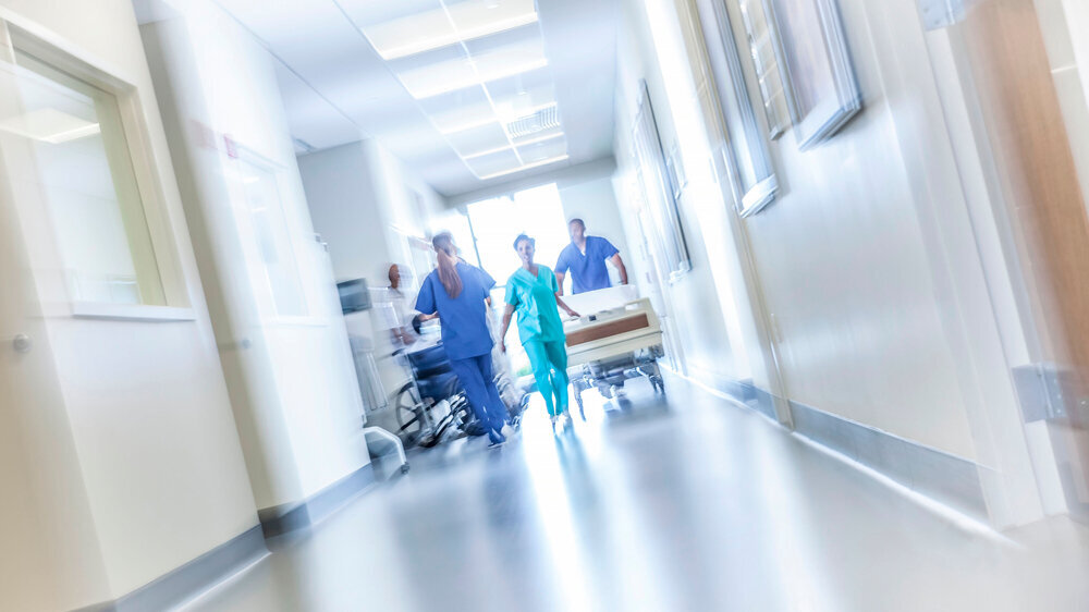 African American male female medical nursing staff hospital corridor motion blur African American male female medical nursing staff with hospital bed in specialist care corridor motion blur