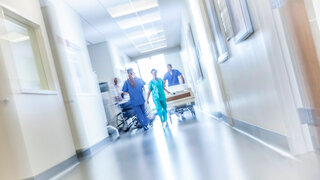 African American male female medical nursing staff with hospital bed in specialist care corridor motion blur