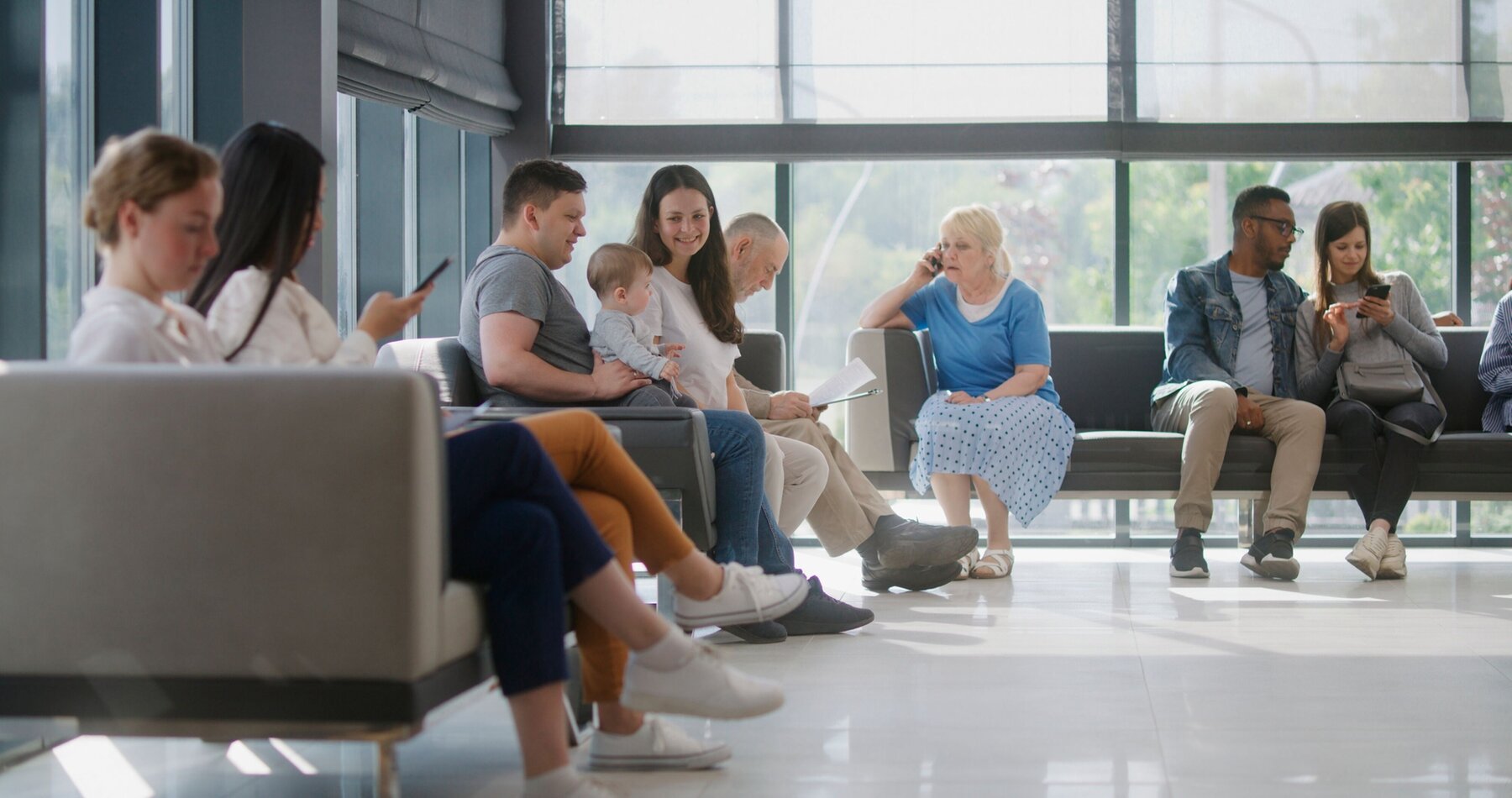 Verschiedene Menschen sitzen im Wartebereich einer Arztpraxis