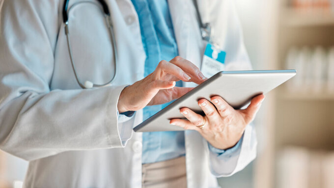 Ein Arzt hält ein Tablet für die Recherche in den Händen als Teil der Telematikinfrastruktur.