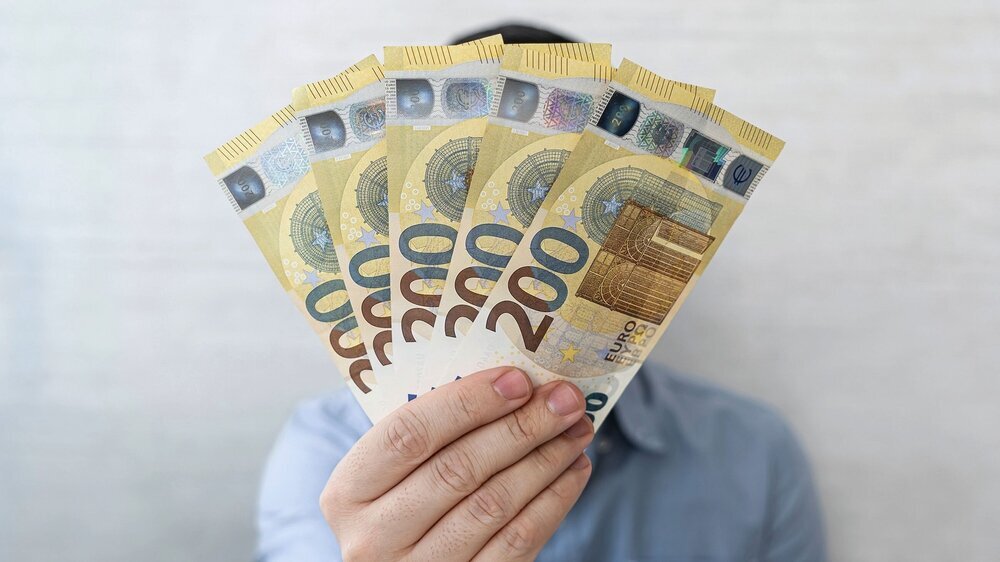 dollars in hands. Businessman in blue shirt holding a 1000 euros. a fan of money Mann hält fünf 200-Euro-Scheine in die Kamera