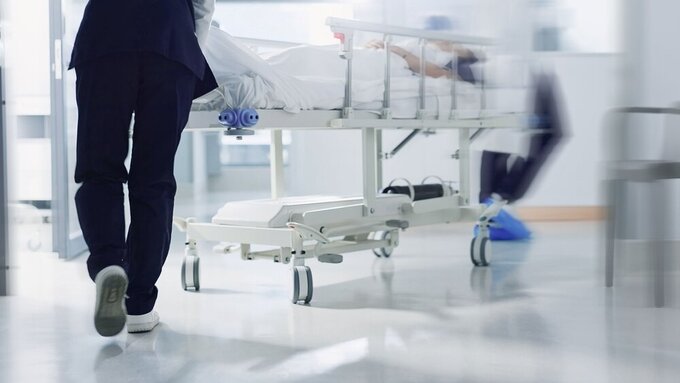 Healthcare, doctor and rush bed in hospital for surgery, emergency or medical problem in corridor. Medicine, professional and nurse feet with stretcher for wellness, service and risk in clinic or job Krankenhaus
