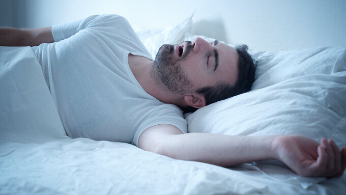 Man sleeping in his bed and snoring loudly Symbolfoto schnarchender Mann