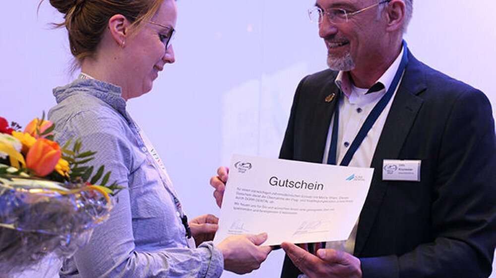 Udo Kronester, Geschäftsführer Mercy Ships Deutschland e.V., überreicht den Gutschein für einen vierwöchigen Hilfseinsatz mit dem Dental Team von Mercy Ships, gesponsert von der Firma Dürr Dental, an Gewinnerin Christina Feußner.