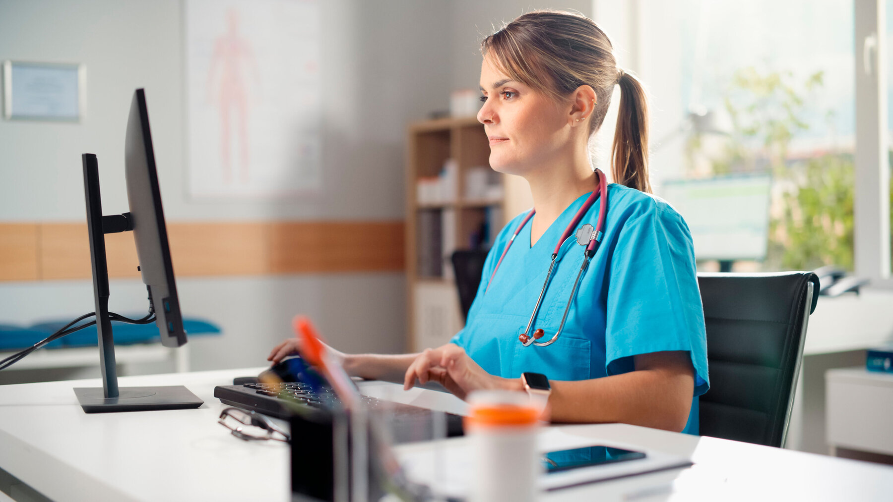 Hispanic Doctor's Office: Experienced Head Nurse Sitting at Her Desk Working on Personal Computer. Medical Health Care Specialist Filling Prescription Forms, Checking Analysis Test Results.