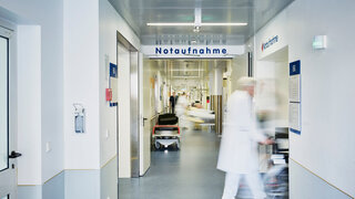 Notaufnahme Eingang Krankenhaus mit Arzt Rollstuhl und Patient in Bewegungsunschärfe auf dem Flur
