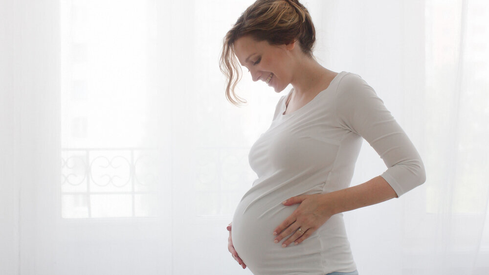Schwangere Frau berührt ihren Bauch.