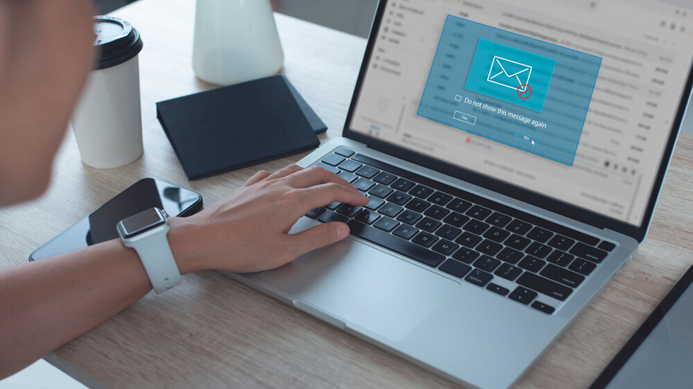 Blocking spam e-mail, warning pop-up for phishing mail, network security concept. Business woman working on laptop computer at home with warning window on screen
