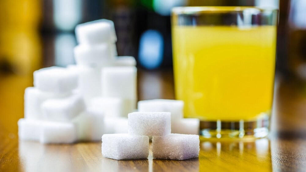 ein Glas mit Saft und viel Würfelzucker sind auf einem Tisch ein Glas mit Saft und viel Würfelzucker sind auf einem Tisch