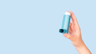 Eine Hand hält einen Asthma-Inhalator.