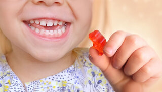 small child smiles openly, blonde girl 3 years old wants to eat gelatinous sweets, gummy bear, kid has a good appetite, happy childhood, balanced diet, sweet life, unhealthy food, halal food