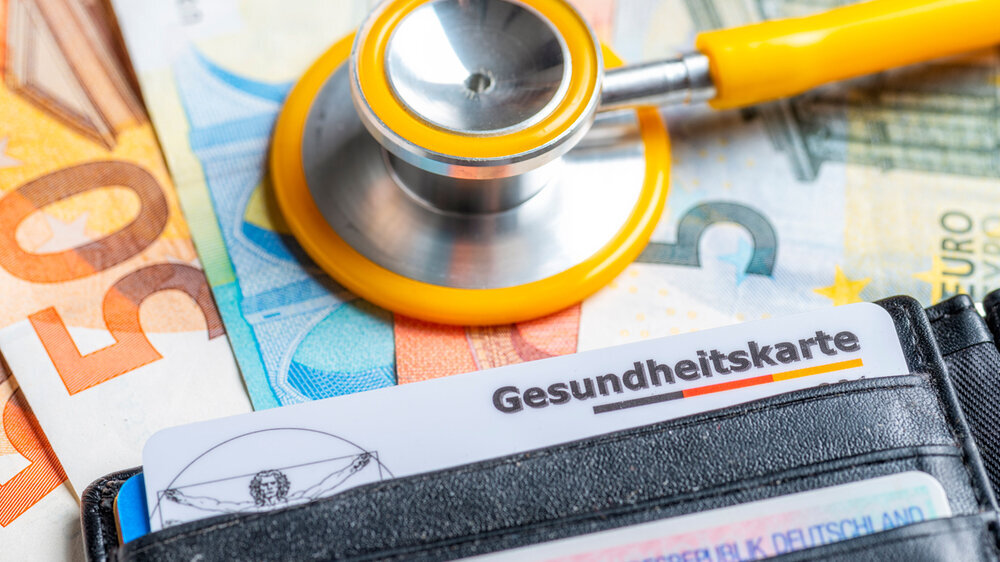 Gesundheitskarte mit Geldscheinen und Stethoskop Gesundheitskarte mit Geldscheinen und Stethoskop
