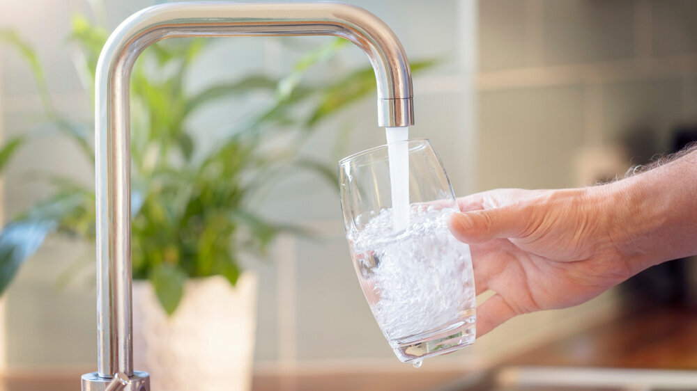 Mann füllt Glas mit Leitungswasser auf Mann füllt Glas mit Leitungswasser auf